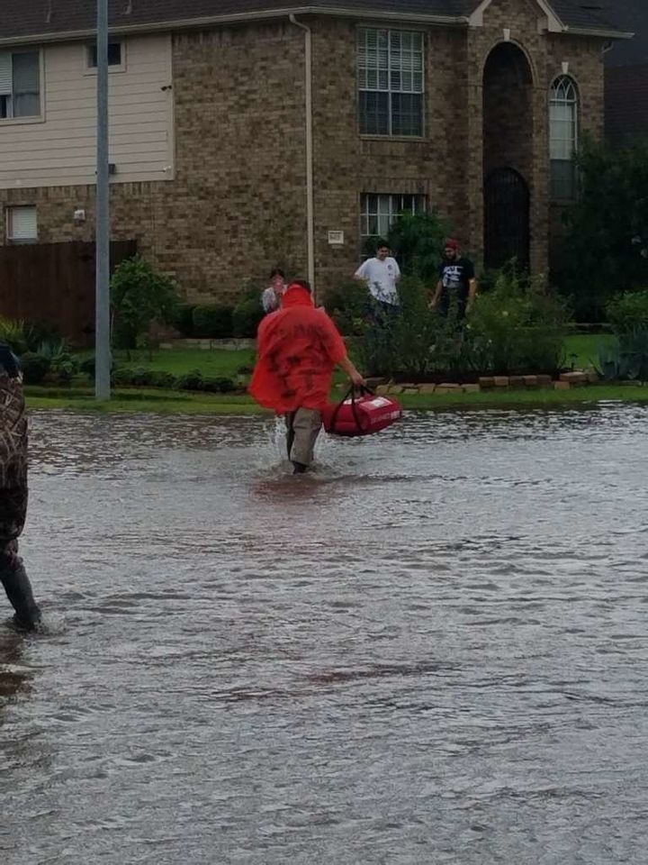 A man delivers pizza to a home surrounded by water.