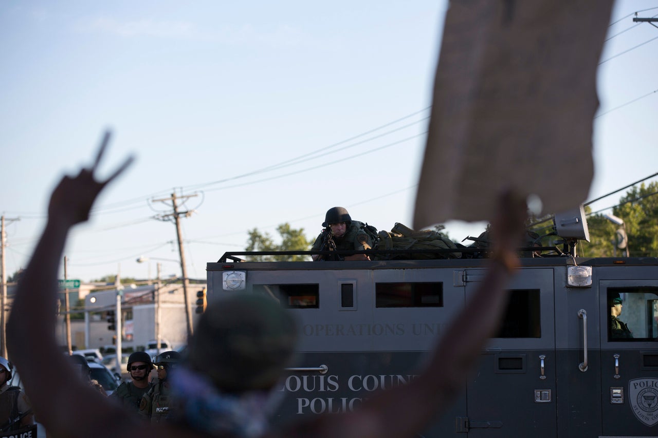 A police officer aims his weapon at a demonstrator in Ferguson, Aug. 13, 2014.