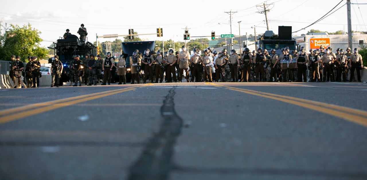 Police officers keep watch while demonstrators (not pictured) protest the death of black teenager Michael Brown in Ferguson, Missouri, Aug. 12, 2014.