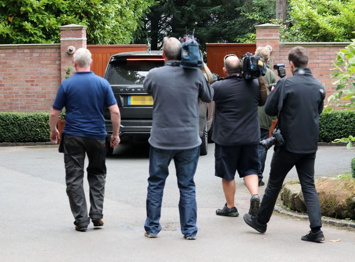Cameramen follow a car as it pulls into Rooney's home