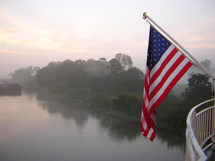 An American Flag in the early morning light near a levee on the Mississippi River.