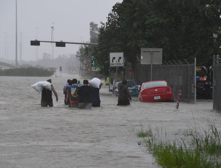 People walk through water to escape from their homes on Highway 90 after Hurricane Harvey caused heavy flooding in Houston, Texas on Aug. 28, 2017.