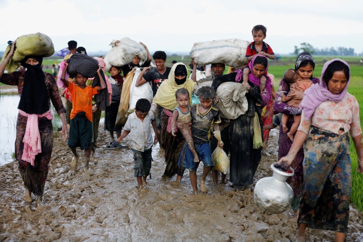 A group of Rohingya refugees walk on the muddy road after travelling over the Bangladesh-Myanmar border in Teknaf, Bangladesh