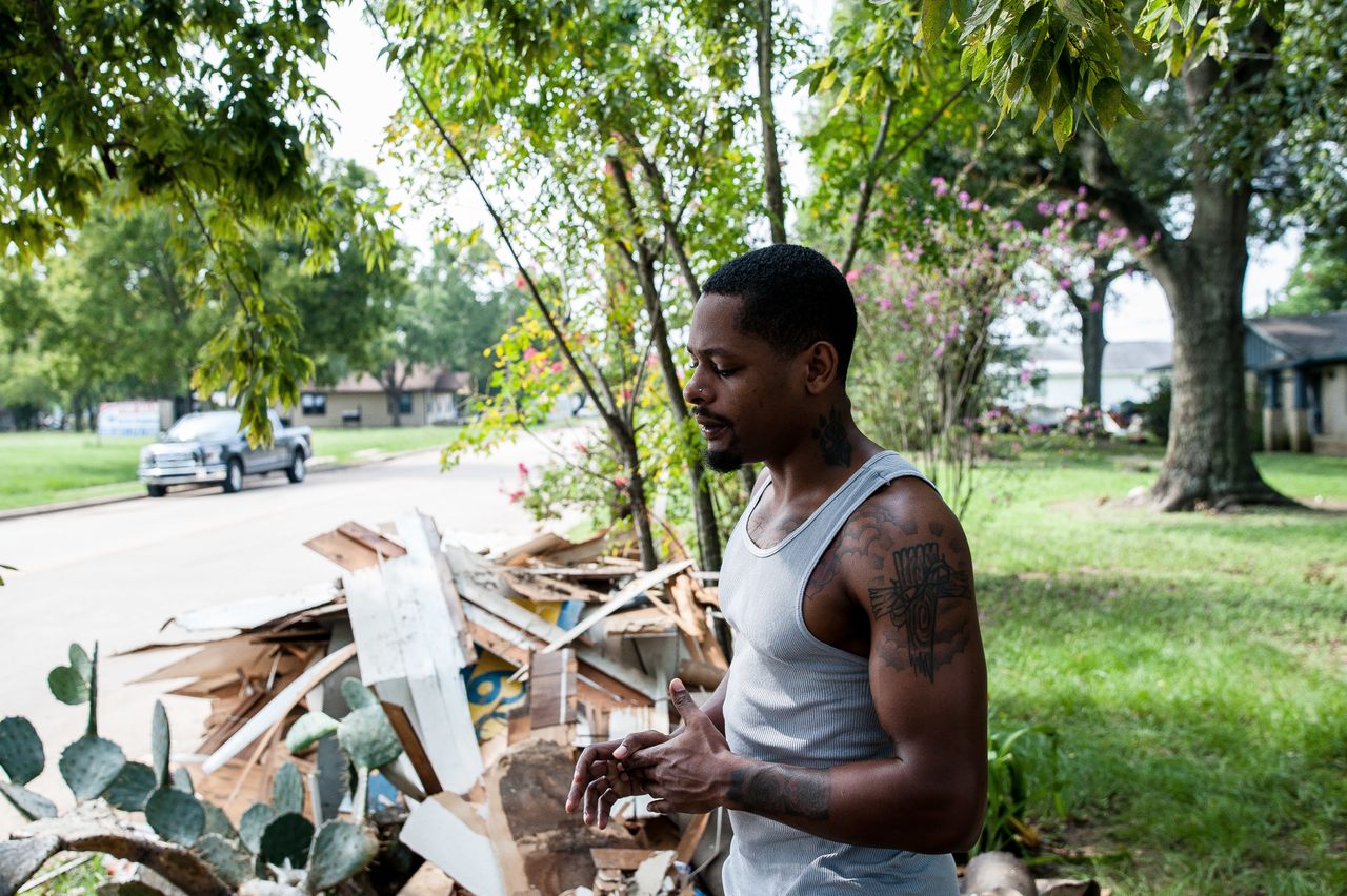 Damion Lasker, 24, stands next to debris on Sunday taken from his mother's flooded home in Katy, Texas, west of Houston. Houses on every street in this town have similar piles waiting for pickup.