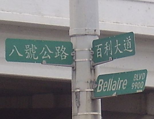 The Chinese sign on the left is for Beltway 8; the one on the right is for Bellaire Boulevard.