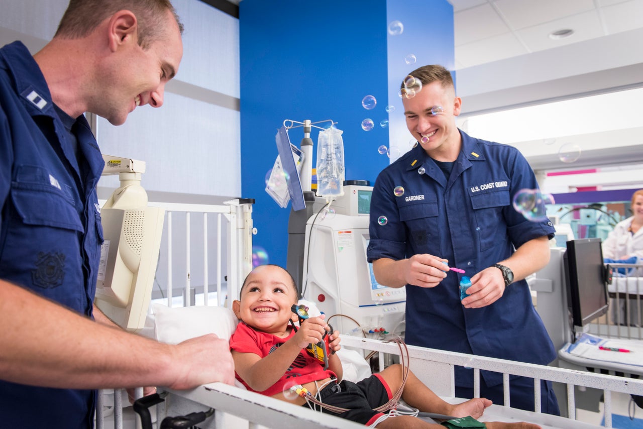 Coast Guard Lt. Brad Bryan (left) and Ensign James Gardner play with Zaiden Thomas, a dialysis patient who the two Guardsmen helped rescue during the floods caused by Hurricane Harvey. On Labor Day, the pair met some of the patients they delivered to Texas Children's Hospital in Houston and the staff with whom they coordinated the missions.