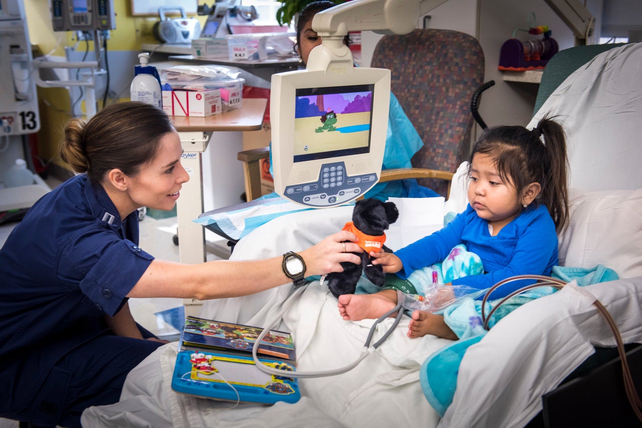 Cook hands a plush toy to a dialysis patient at the hospital on Labor Day.