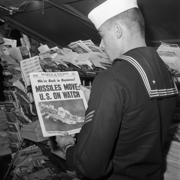 U.S. sailor reads the front page of the New York Daily News at a newsstand on November 9, 1962.