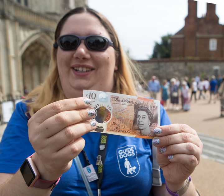 Jemma Brown, from the Guide Dogs association, tests the brail on the new £10 note