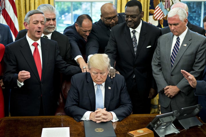 President Trump bows his head during a prayer while surrounded by U.S. Vice President Mike Pence, faith leaders and evangelical ministers after signing a proclamation declaring a day of prayer in the Oval Office of the White House in Washington, D.C., U.S., on Friday, Sept. 1, 2017.