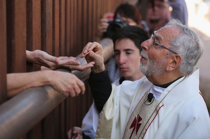 Bishop of Tucson Gerald Kicanas passes communion wafers through to the Mexican side of the U.S.-Mexico border fence during a special 'Mass on the Border' on April 1, 2014 in Nogales, Arizona.