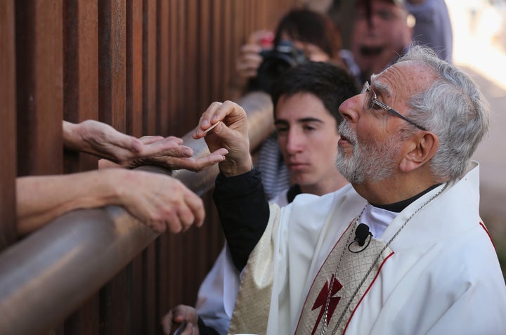 Bishop of Tucson Gerald Kicanas passes communion wafers through to the Mexican side of the U.S.-Mexico border fence during a special 'Mass on the Border' on April 1, 2014 in Nogales, Arizona.