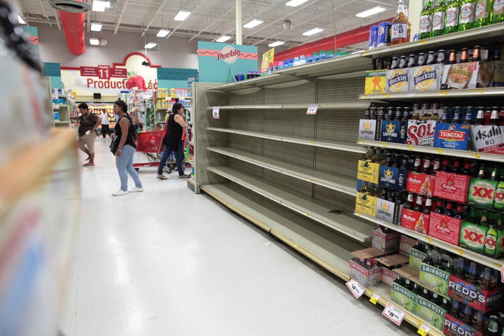Customers in San Juan walk near empty shelves that are normally filled with bottles of water after Puerto Rico Gov. Rica