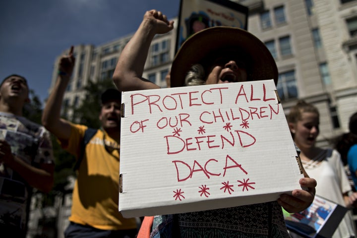 A demonstrator yells while holding a sign protesting the end of the DACA program outside Trump International Hotel in Washing