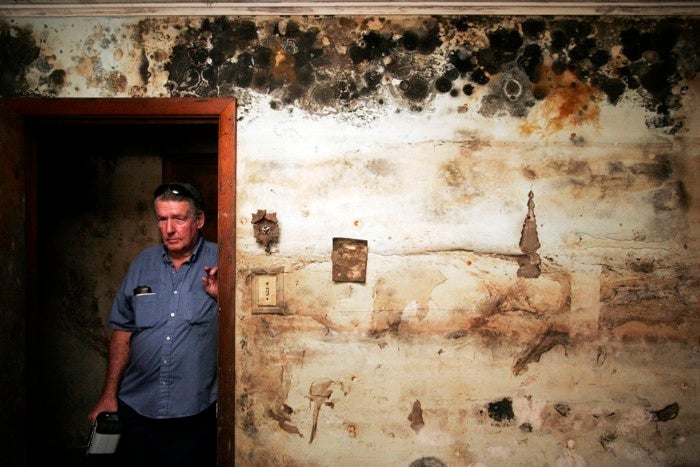 Two years after Hurricane Katrina, a New Orleans resident poses in his mold-infested home. 