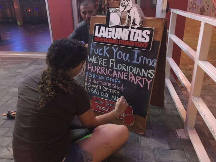 A bar employee in Fort Lauderdale scrawls a sign announcing a Hurricane Irma party.