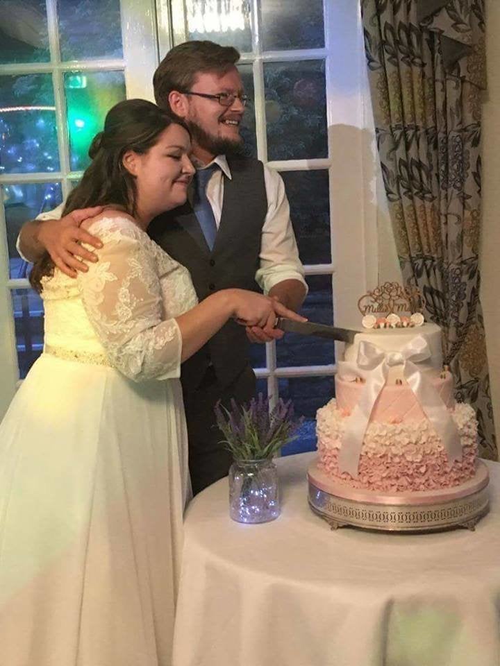 The newlyweds cutting the repaired cake. 