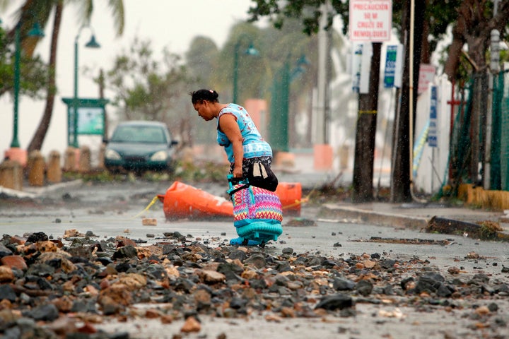 A woman pulls a suitcase along on a rock-strewn road in the aftermath of Hurricane Irma in Fajardo, Puerto Rico, on Thursday.