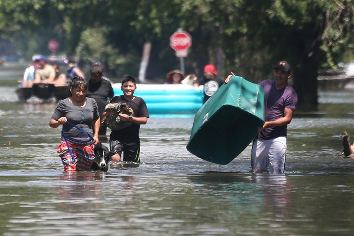 People walk with their possessions out of a flooded area of Port Arthur, Texas on Aug. 31, 2017.