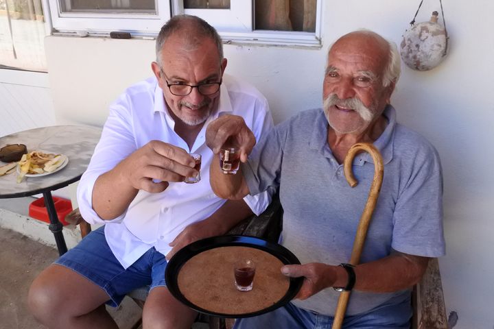 <p>My husband and Iorgos sharing a glass of Rakomelo.</p>