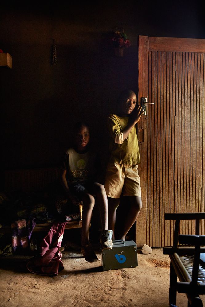 Jan Chumba (12) and his brother Ben (10) in the doorway of their home, Chiuta village, southern Malawi, 2017. During the day, the only light inside comes from the open door and windows. 