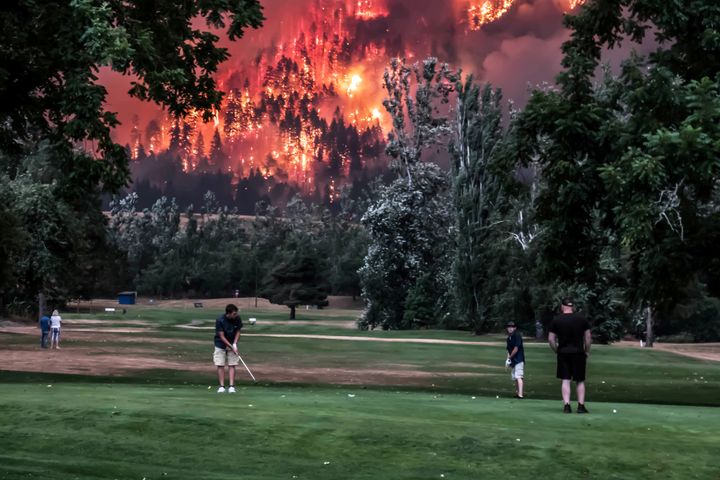 The Eagle Creek wildfire burns as golfers play at the Beacon Rock Golf Course in North Bonneville, Washington, on September 4, 2017.