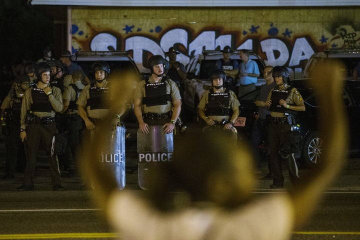 St Louis County police officers watch as anti-police demonstrators march in protest in Ferguson, Missouri August 10, 2015.