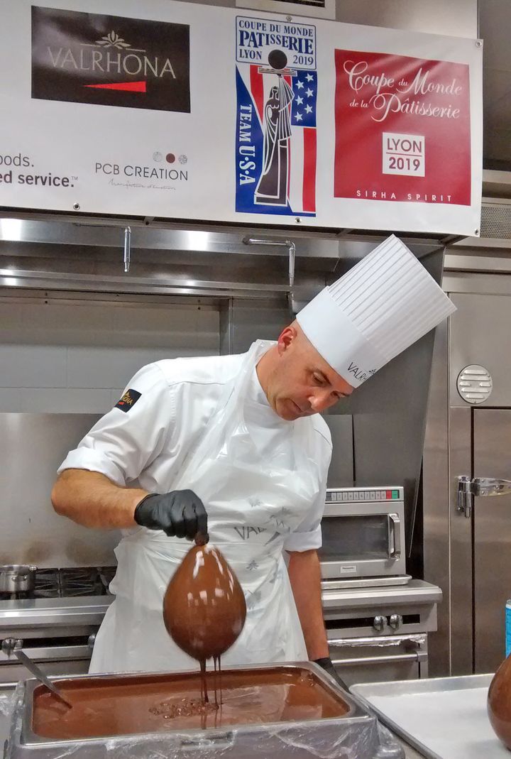 <p>Olivier Saintemarie dips balloons in tempered chocolate to create the hourglass for his chocolate showpiece </p>