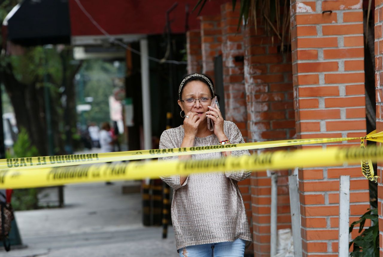A woman talks on the phone near a damaged building 