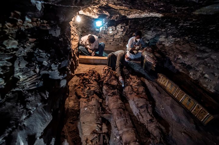 A picture taken on September 9, 2017 shows Egyptian labourers and archaeologists unearthing mummies at a newly-uncovered ancient tomb for a goldsmith dedicated to the ancient Egyptian god Amun, in the Draa Abul Naga necropolis on the west bank of the ancient city of Luxor, which boasts ancient Egyptian temples and burial grounds.