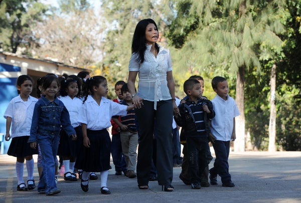 A teacher guides her pupils to the classroom on the first day of classes in Honduras, at the John F. Kennedy School in Teguci