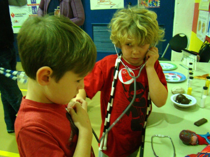 <p>With a jump rope around his and a stethoscope in his ears, one of Kris’ students listens to another’s heart beat.</p>