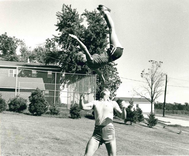 <p>Kris doing a bird flip with Chuck, her fellow cheerleader and circus performer who would become her husband.</p>