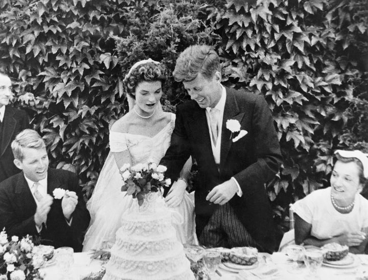 The couple cut their wedding cake at the reception. Kennedy's brother Robert Kennedy (left) looks on.