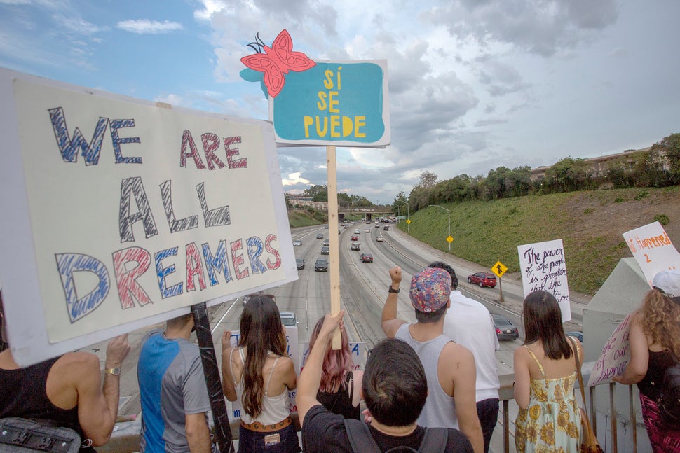 People hold signs over the 110 Freeway in Los Angeles as thousands of immigrants and supporters join the Defend DACA March to