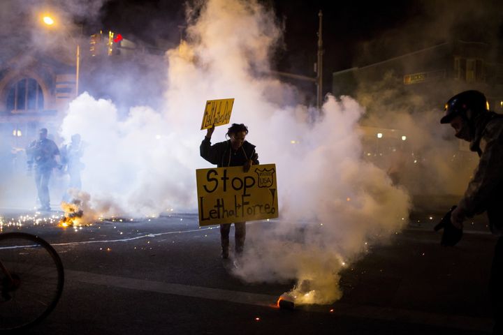 Clouds of smoke and crowd control agents rise around a protester shortly after the deadline for a city-wide curfew passed in Baltimore in April 2015.