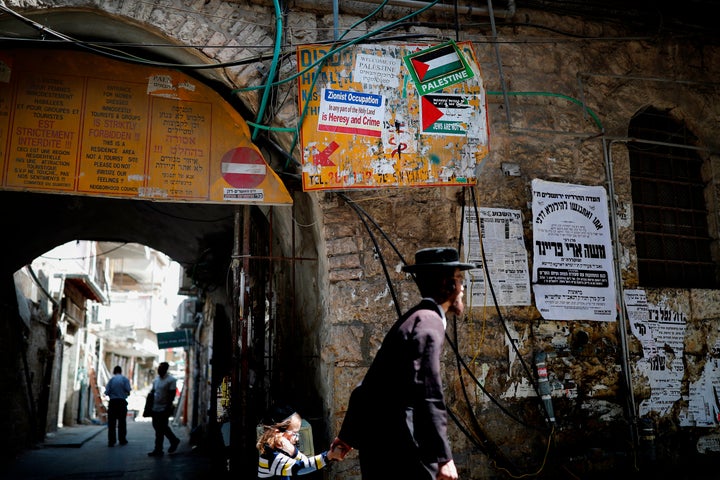 A picture taken on September 13, 2017, shows an Ultra-Orthodox Jew passing by some signs against the Israeli State and Zionist occupation, in the Ultra-Orthodox neighborhood of Mea Shearim of Jerusalem.