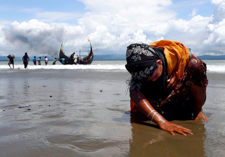 An exhausted Rohingya refugee woman touches the shore after crossing the Bangladesh-Myanmar border by boat on Sept. 11, 2017.