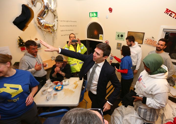 Burnham, throws a winter hat to a homeless person during a visit to the Barnabus Centre in Manchester