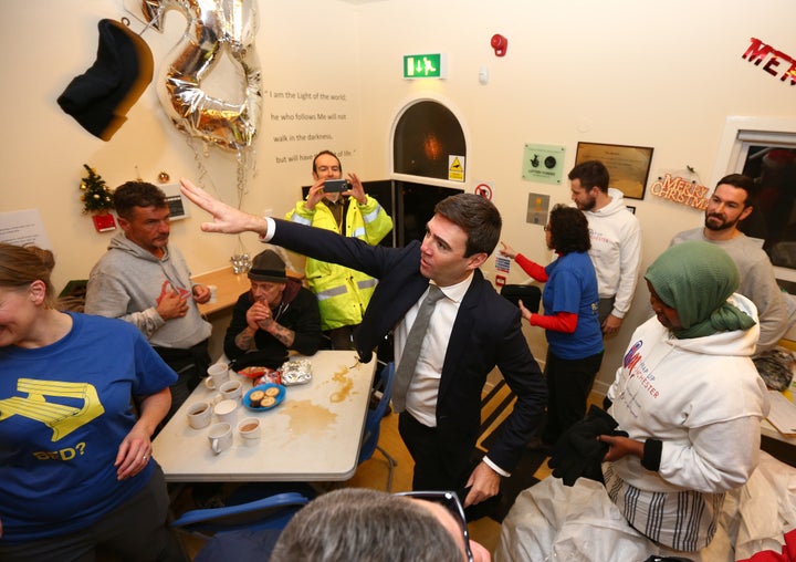 <strong>Burnham, throws a winter hat to a homeless person during a visit to the Barnabus Centre in Manchester</strong>