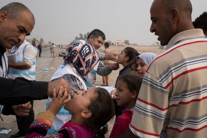 Displaced children, who fled villages south of Mosul, Iraq, receive drops of oral polio vaccine from health workers on Oct. 24, 2016. 