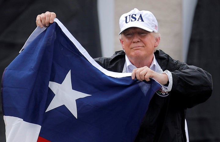 President Donald Trump holds the Texas flag after receiving a briefing on Tropical Storm Harvey relief efforts in Corpus Christi, Texas, on Aug. 29, 2017.