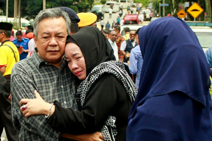 Nik Azlan Nik Abdul Kadir, left, father of one of the victims, comforts his wife after a deadly fire at their child's religio