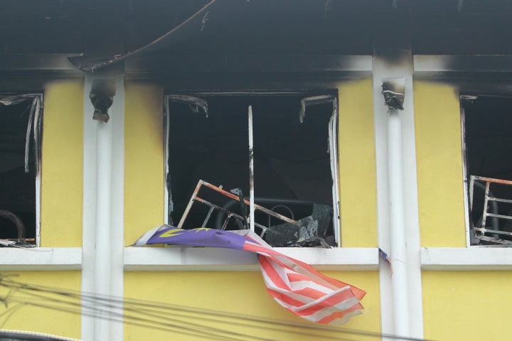 A Malaysian national flag flutters outside the burnt windows of the Darul Quran Ittifaqiyah religious school in Kuala Lumpur