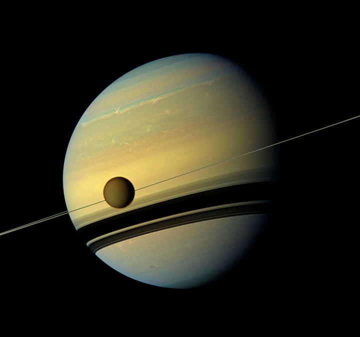 Titan, Saturn's largest moon appears before the planet as it undergoes seasonal changes in this natural colour view from NASA's Cassini spacecraft.