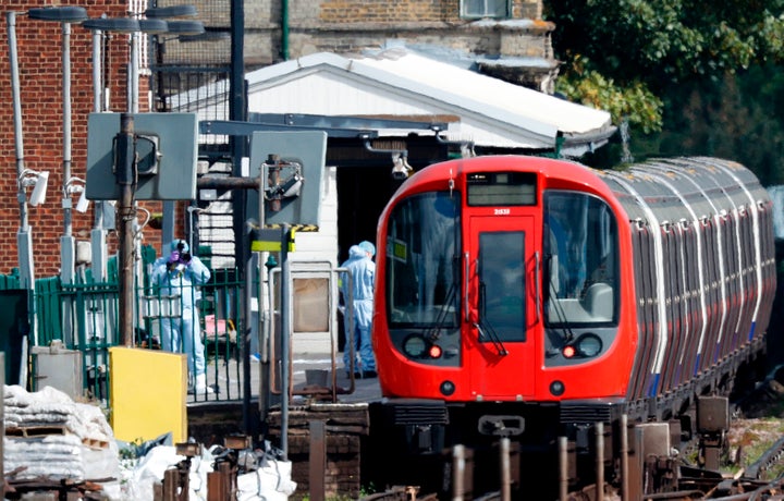 Police forensics officers works alongside an underground tube train at a platform at Parsons Green underground tube station i