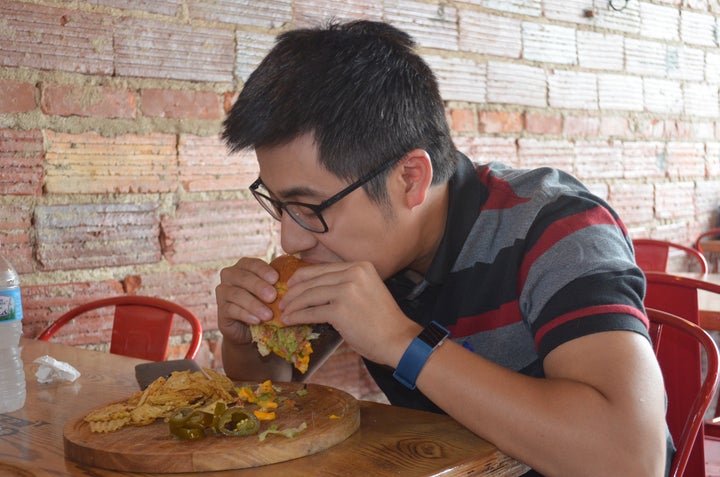 <p>Ricky Mao, a customer at “The Butcher’s Grille & Market” chomps into a <em>Fiesta Burger</em> in downtown West Dearborn, Mich.</p>