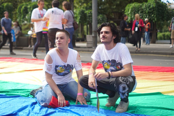 Boys posing for a photo on a gigantic rainbow flag.