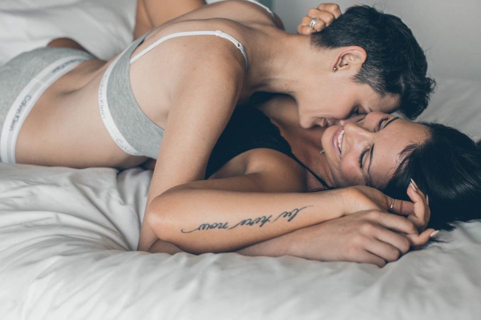 Romantic couple embracing in studio shot, just about to kiss, man is  muscular and shirtless, woman is showing bra under open shirt Stock Photo