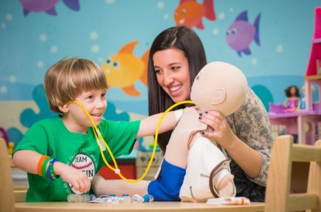 St. Jude patient Griffin plays doctor with a medical doll alongside his child life specialist. (2016)